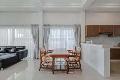 Modern open-layout living room with sleek kitchen and dining area, featuring elegant furniture and natural light.