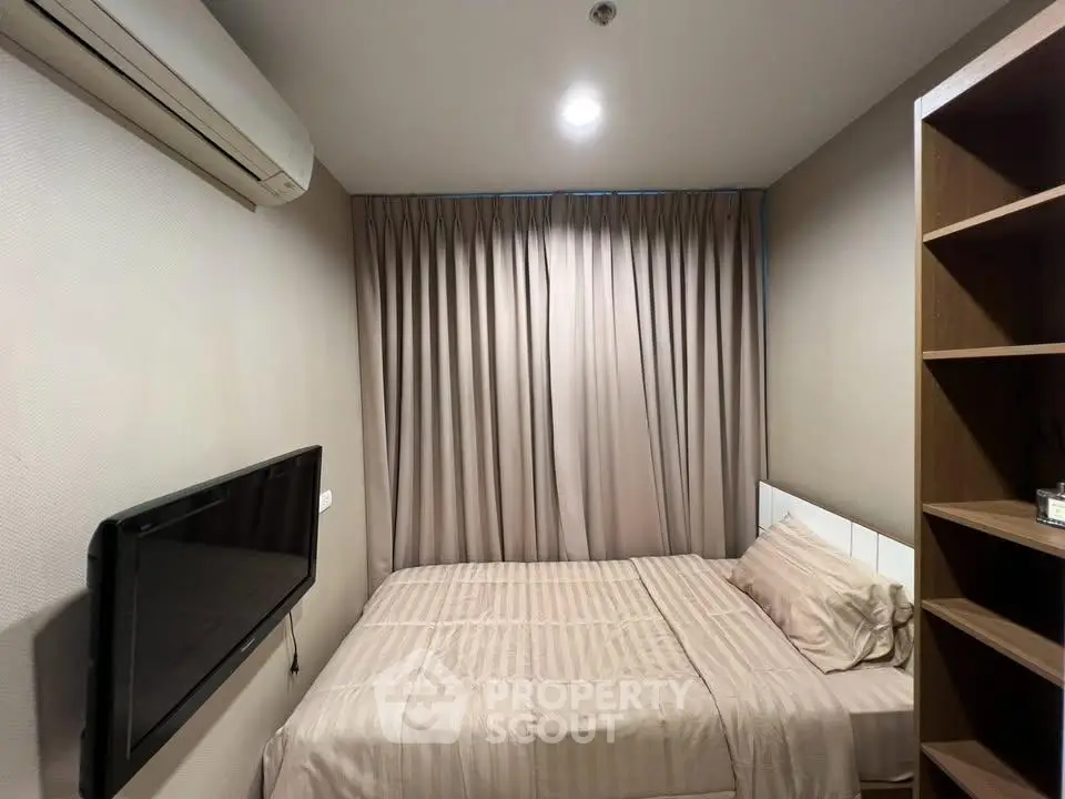 Cozy bedroom with modern decor, featuring a wall-mounted TV and ample storage space.