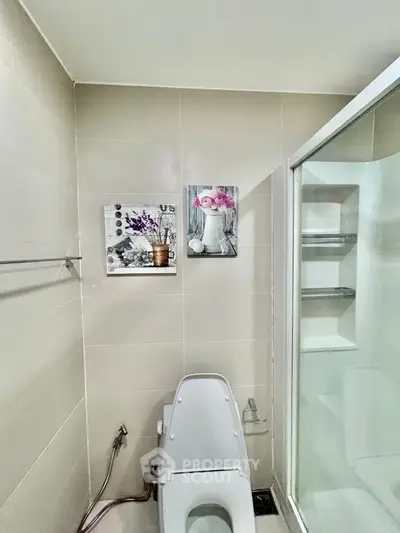 Modern bathroom with sleek toilet and glass shower enclosure, featuring elegant wall art.