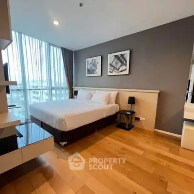 Modern bedroom with large windows and wooden flooring in a stylish apartment.