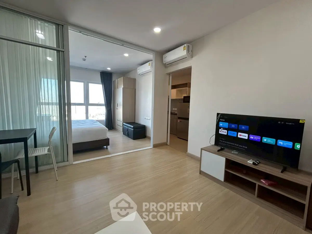 Modern open-plan living room with TV and bedroom view in stylish apartment