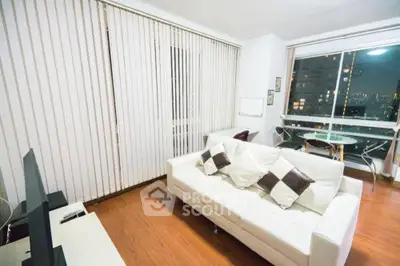 Modern living room with city view, sleek white sofa, and floor-to-ceiling windows.