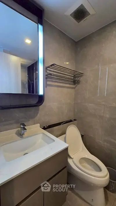 Modern bathroom with sleek fixtures and elegant design, featuring a stylish mirror and contemporary toilet.