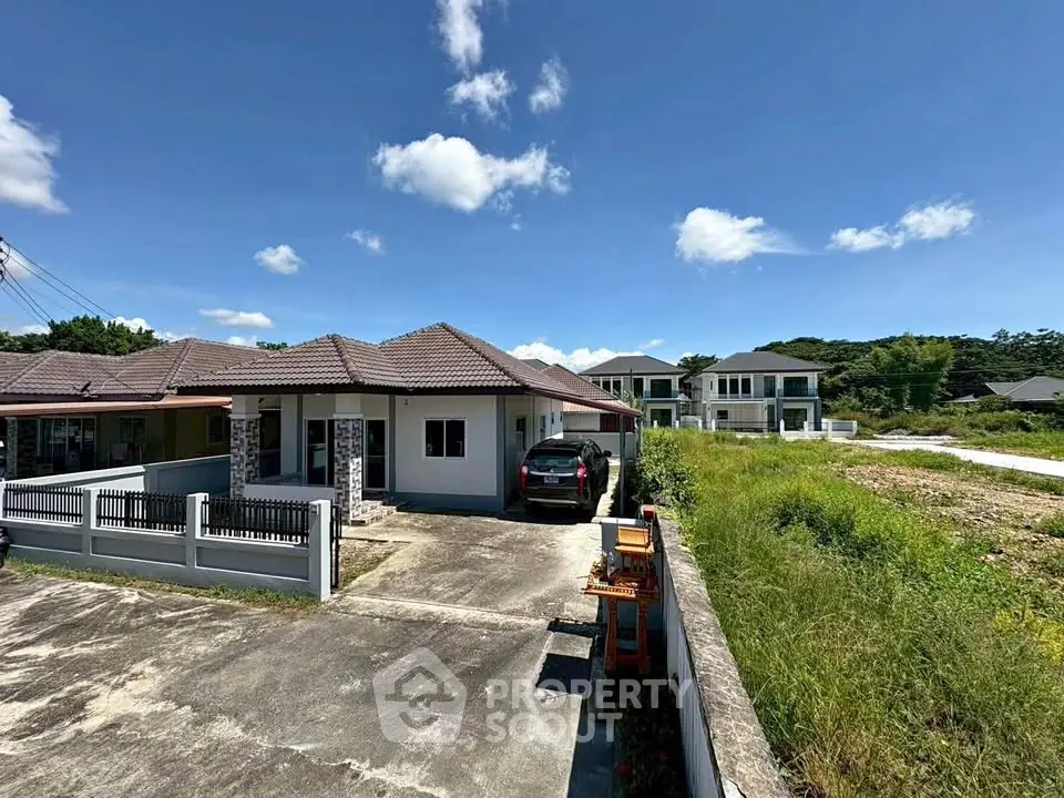 Charming suburban house with spacious driveway and lush surroundings under a clear blue sky.