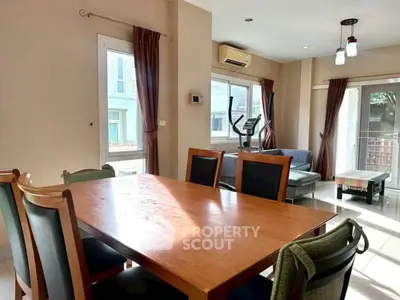 Spacious dining area with large windows and modern furnishings in a bright, airy home.