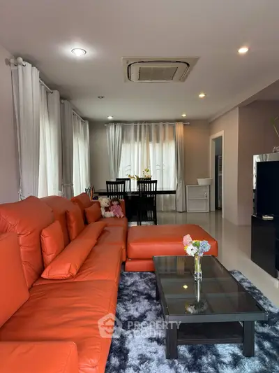 Spacious living room with vibrant orange sofa and modern decor