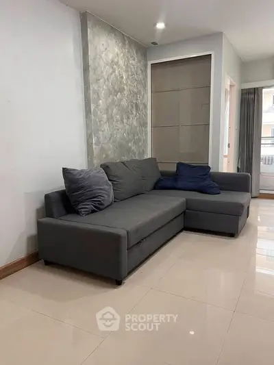 Modern living room with stylish gray sectional sofa and sleek tile flooring
