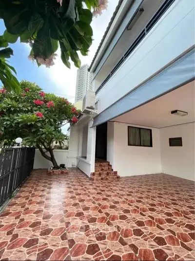 Charming exterior view of a modern home with tiled patio and lush greenery.