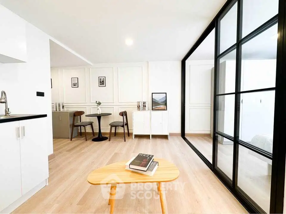 Modern living room with stylish decor and glass partition in a bright apartment.