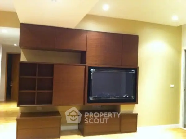 Modern living room with stylish wooden entertainment center and recessed lighting.