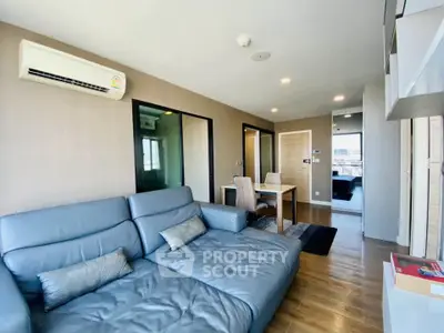 Modern living room with blue leather sofa and dining area in stylish apartment