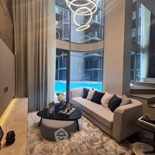 Luxurious living room with modern decor and pool view, featuring elegant lighting and plush furnishings.