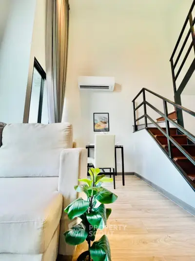 Modern loft-style living room with staircase and cozy seating area.