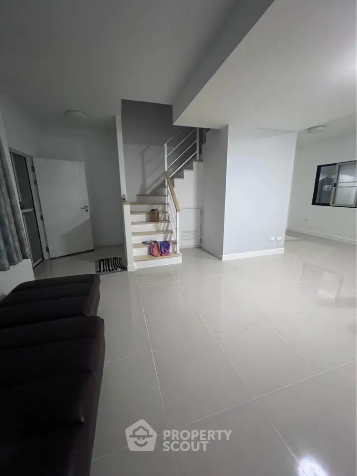 Spacious modern living room with sleek staircase and glossy tiled flooring