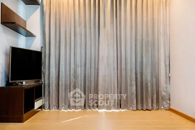 Modern living room with sleek TV setup and elegant floor-to-ceiling curtains.