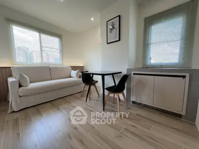 Modern living room with sleek furniture and natural light, featuring a cozy sofa and stylish dining area.