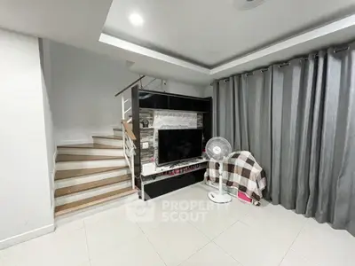 Modern living room with sleek staircase and entertainment center