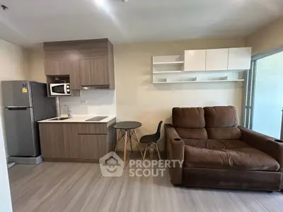 Modern living room with compact kitchen and cozy sofa in open layout apartment.