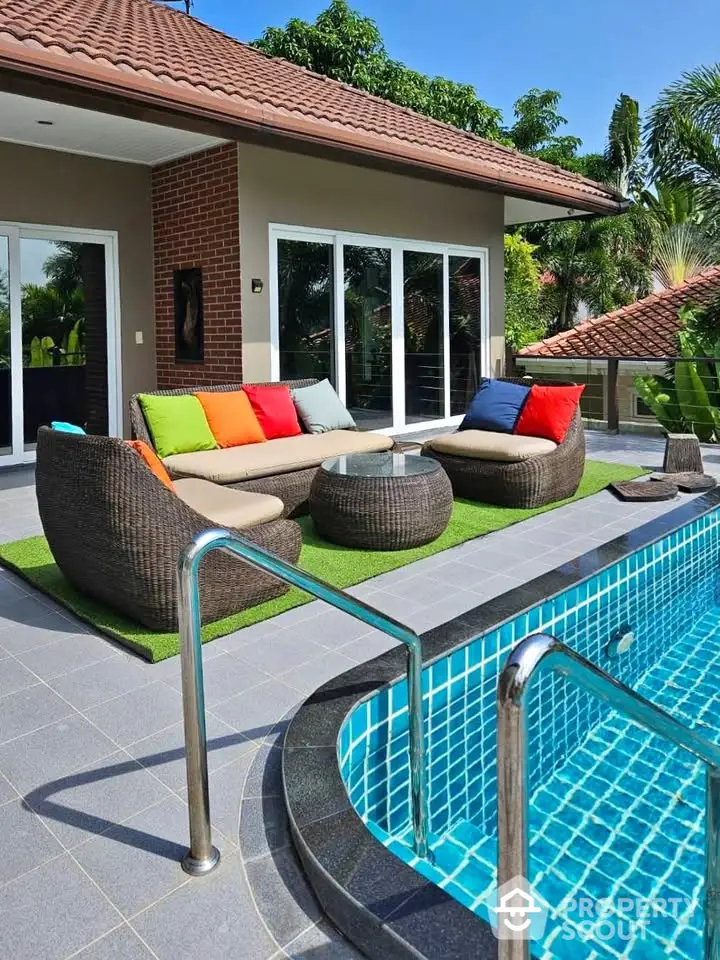 Luxurious poolside patio with stylish outdoor seating and vibrant cushions, perfect for relaxation and entertainment.