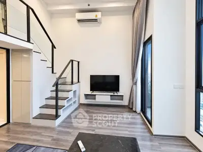 Modern duplex living room with sleek staircase and large windows