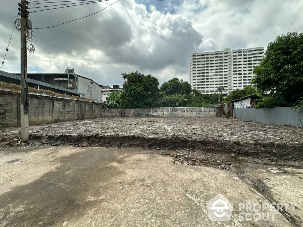 Vacant land plot with urban backdrop, ideal for development, surrounded by greenery and cityscape views.