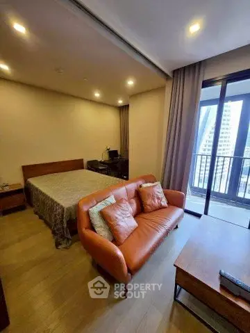 Modern studio apartment with cozy living area and balcony view in urban setting.
