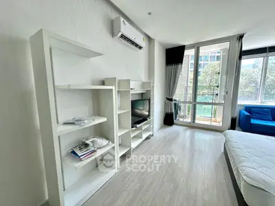 Modern living room with sleek white shelving, air conditioning, and large windows offering natural light.