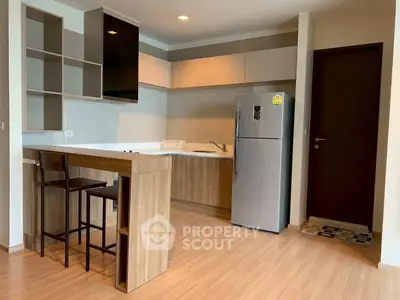 Modern kitchen with sleek cabinetry and stainless steel fridge in a stylish apartment.