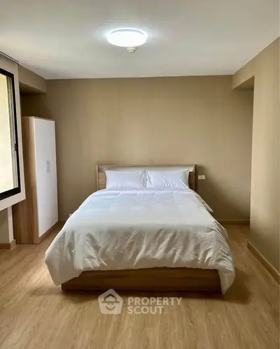 Spacious bedroom with modern design and natural light, featuring a comfortable bed and wooden flooring.