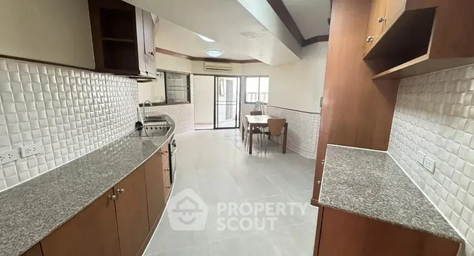 Spacious kitchen with granite countertops and dining area in modern apartment.