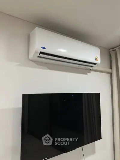 Modern living room with wall-mounted air conditioner and flat-screen TV.