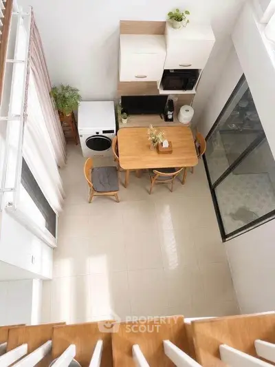 Modern kitchen with open layout, featuring dining table, washing machine, and sleek cabinetry.