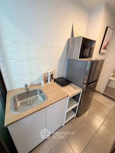 Compact kitchen with modern appliances and sleek design, featuring a stainless steel sink and ample storage.