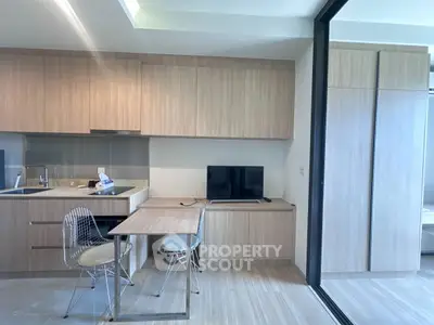 Modern kitchen with sleek cabinetry and dining area in open layout apartment.