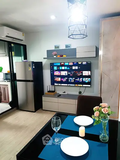 Modern living room with smart TV, dining setup, and sleek kitchen appliances in a cozy apartment.