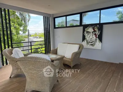 Stylish balcony with wicker furniture and modern art, offering a serene outdoor retreat with lush views.