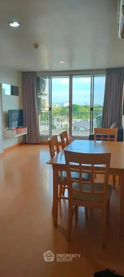 Spacious living room with dining area and balcony view in modern apartment.