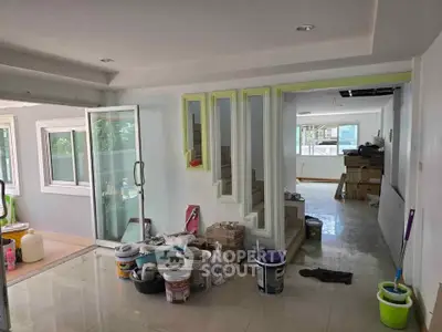 Spacious interior under renovation with modern glass door and ample natural light.