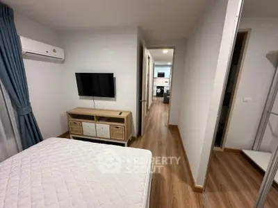 Modern bedroom with wooden flooring, wall-mounted TV, and air conditioning in a cozy apartment.