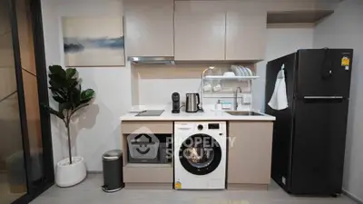 Modern kitchen with sleek appliances including washing machine, microwave, and fridge in stylish apartment.