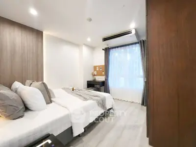 Modern bedroom with stylish decor and natural light through large window.