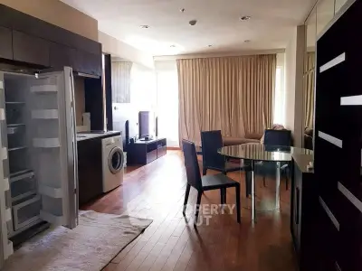 Modern living room with open kitchen, featuring hardwood floors and natural light.