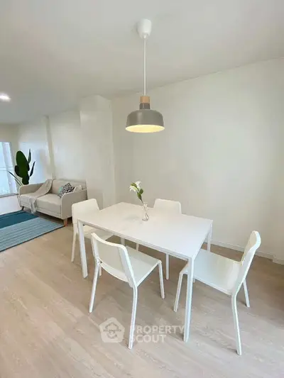 Modern minimalist dining area with white furniture and cozy living space