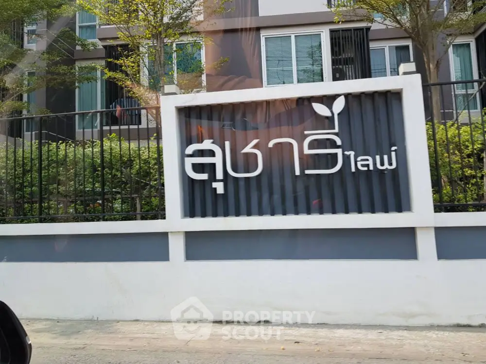 Modern apartment building exterior with stylish signage and lush greenery.