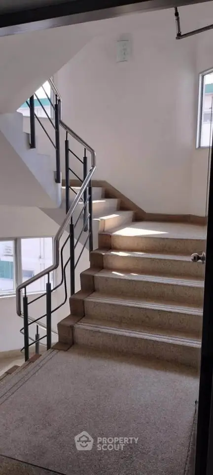 Bright and airy staircase in modern building with sleek metal railings and large windows.