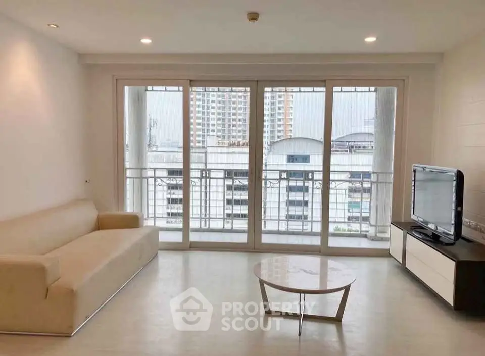 Spacious living room with modern sofa and large windows offering city views.