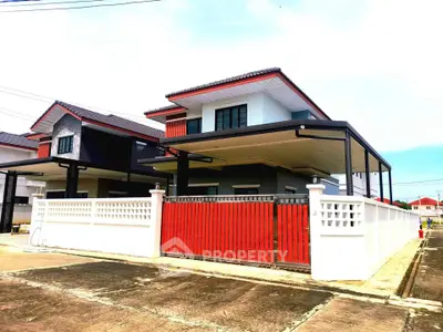 Modern two-story house with red accents and gated driveway in a suburban neighborhood.