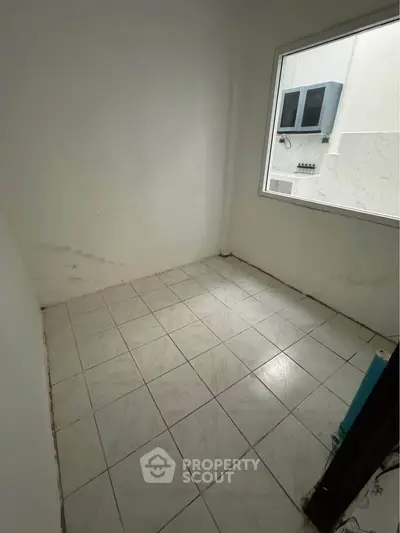 Compact room with tiled floor and window, ideal for storage or small office space.