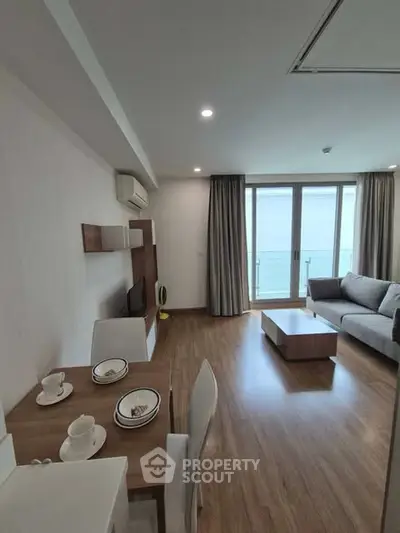 Modern living room with dining area and balcony view in a stylish apartment.