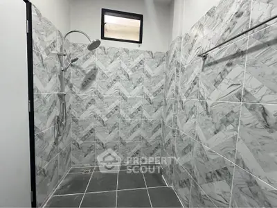 Modern bathroom with stylish marble tiles and sleek shower fixtures.